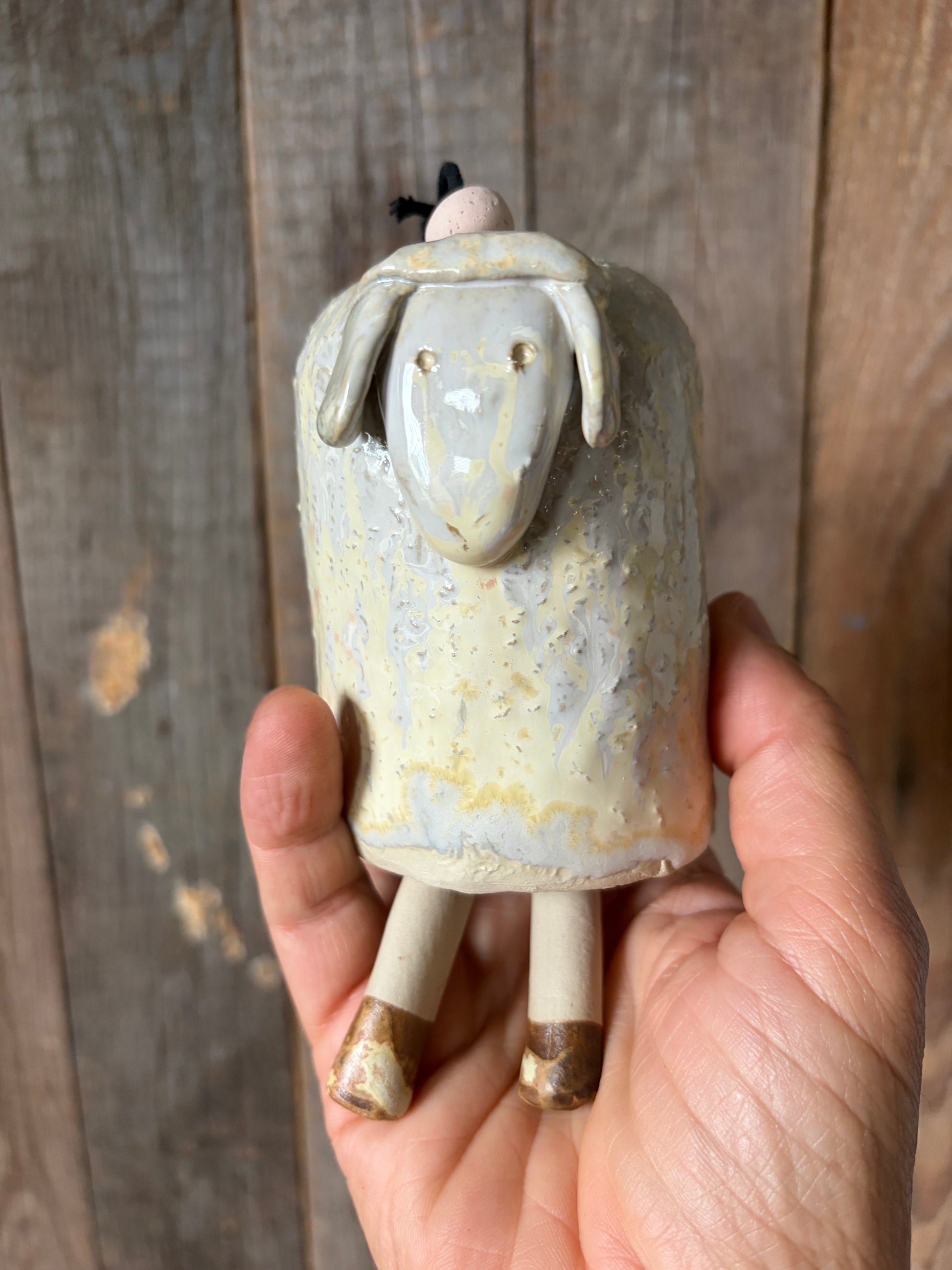 Campanella tintinnante in gres a forma di pecora tenuta in una mano